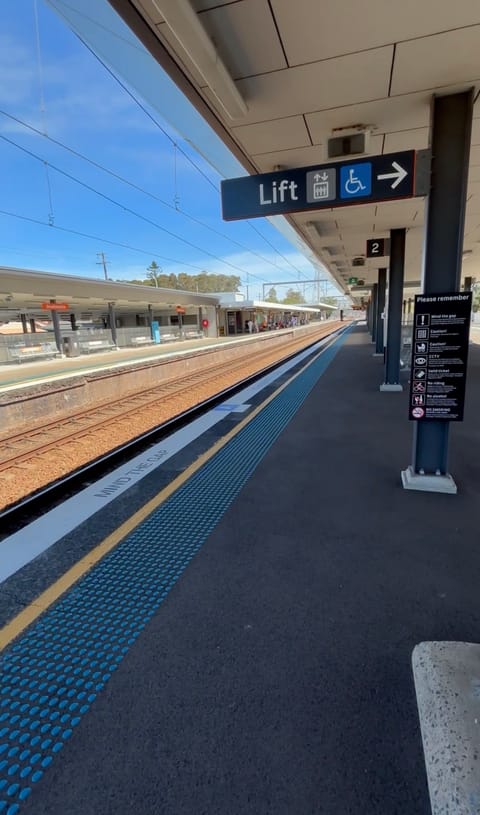 Platform 2, with a blue tactile strip along the platform edge, a "Mind the gap" marking, and a sign pointing to the lift