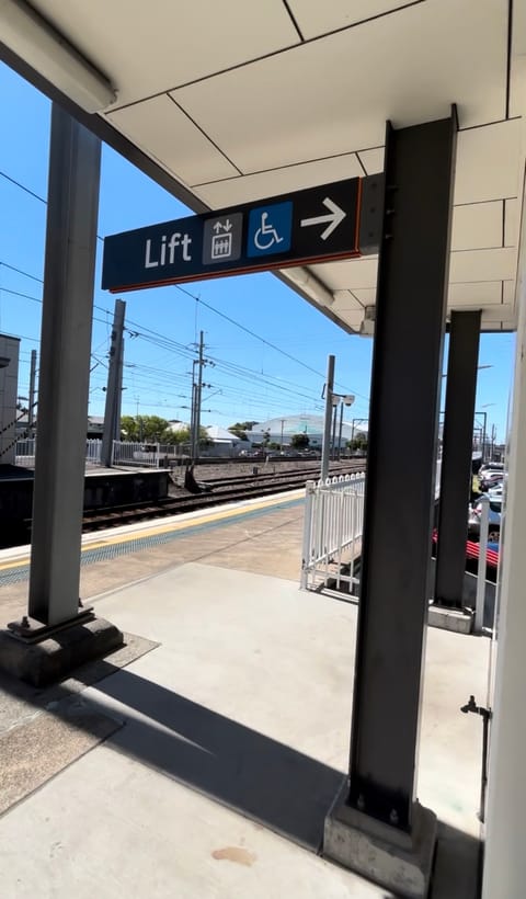 A sign on the platform pointing to the lift, with lift and wheelchair symbols